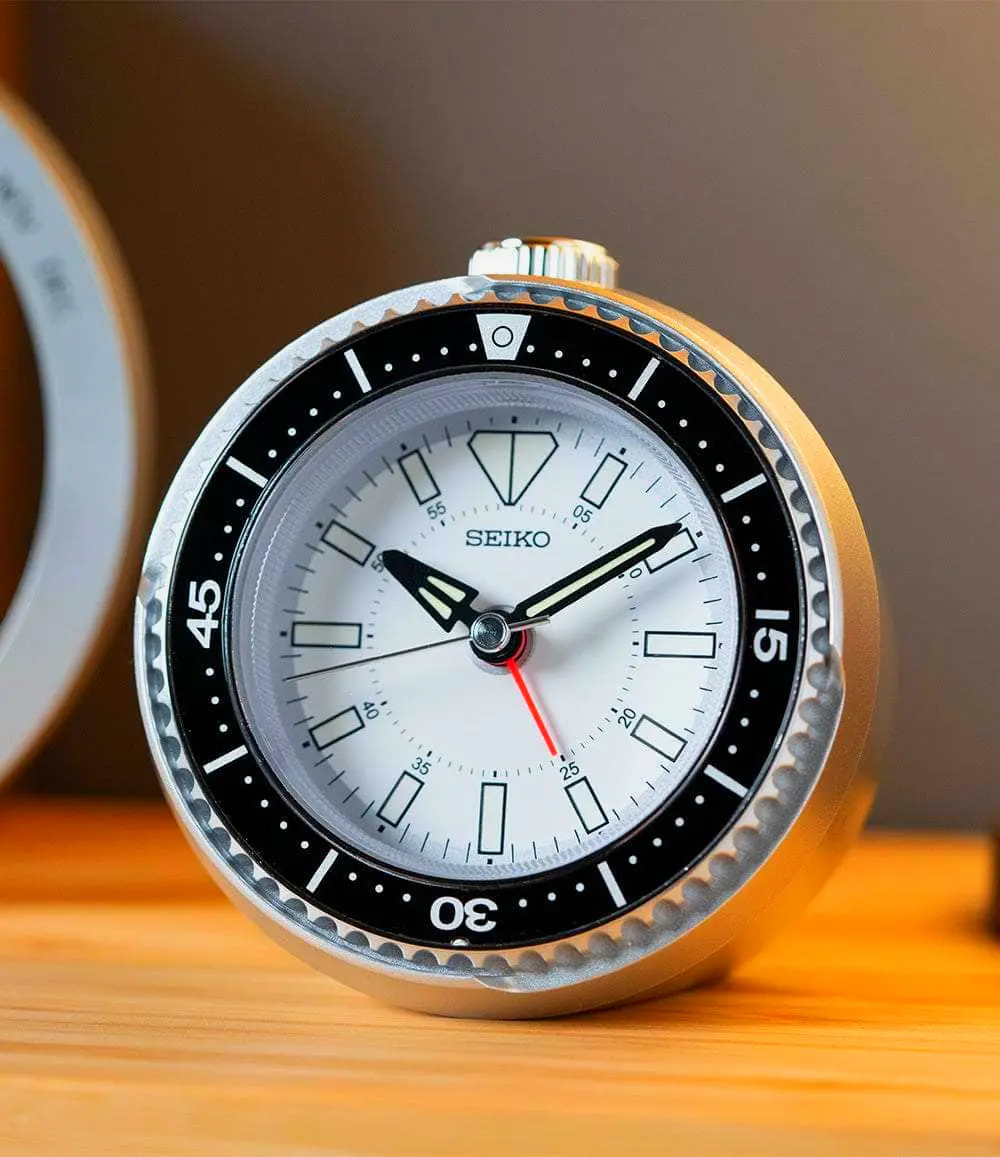 Dark silver black and blue rotating bezel alarm clock for bedroom or office use.